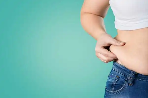 Image of woman pinching her love handles to show weight gain Perth